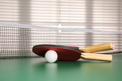 Photo of Rackets and ball on ping pong table indoors