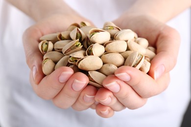 Photo of Woman holding handful of tasty pistachios, closeup