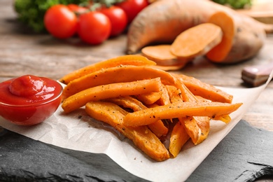 Photo of Slate board with sweet potato fries on table, closeup