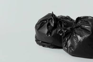 Photo of Trash bags full of garbage on light grey background. Space for text