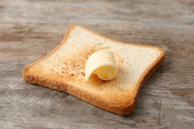 Toasted bread with fresh butter curl on wooden table