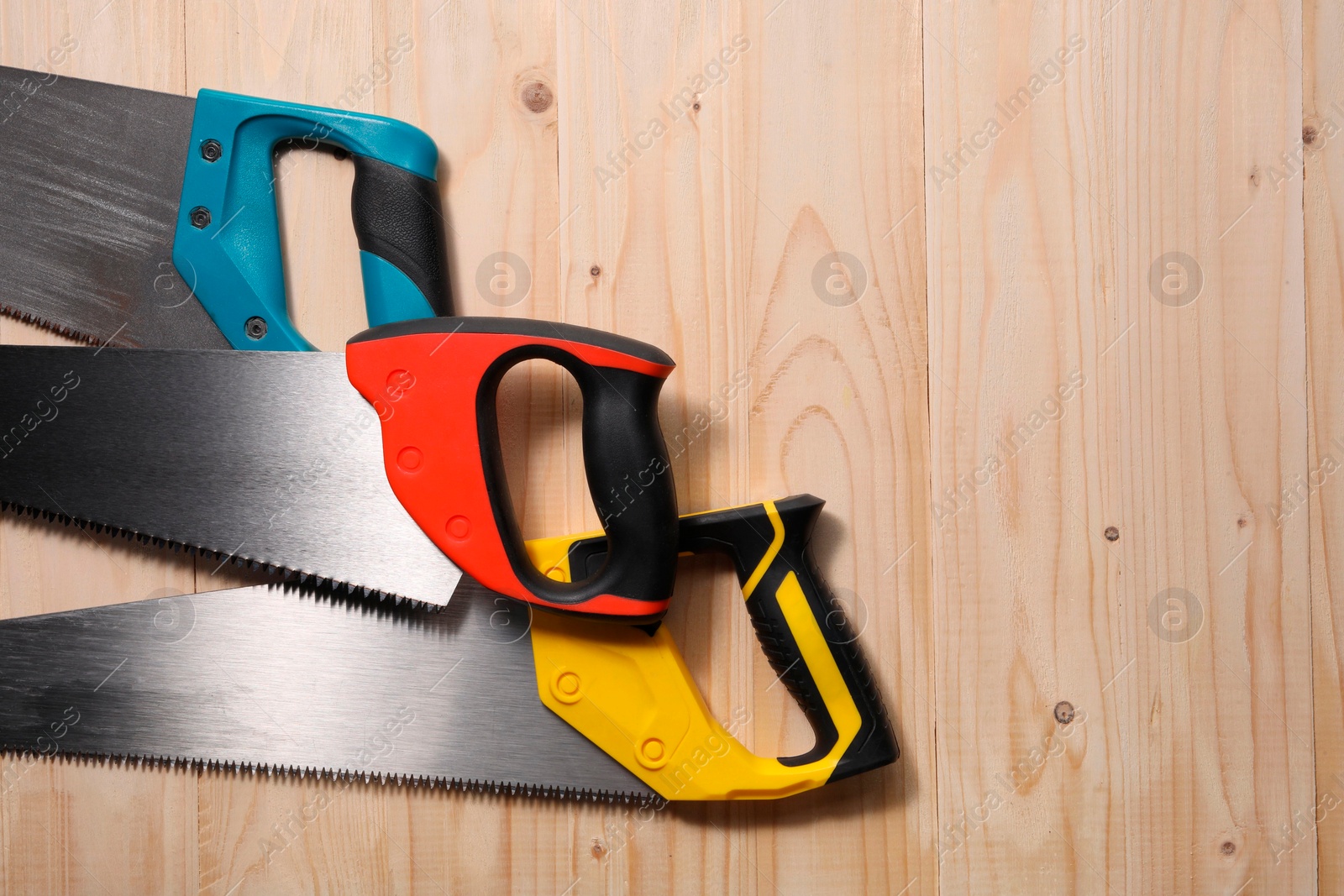 Photo of Saws with colorful handles on wooden background, flat lay. Space for text