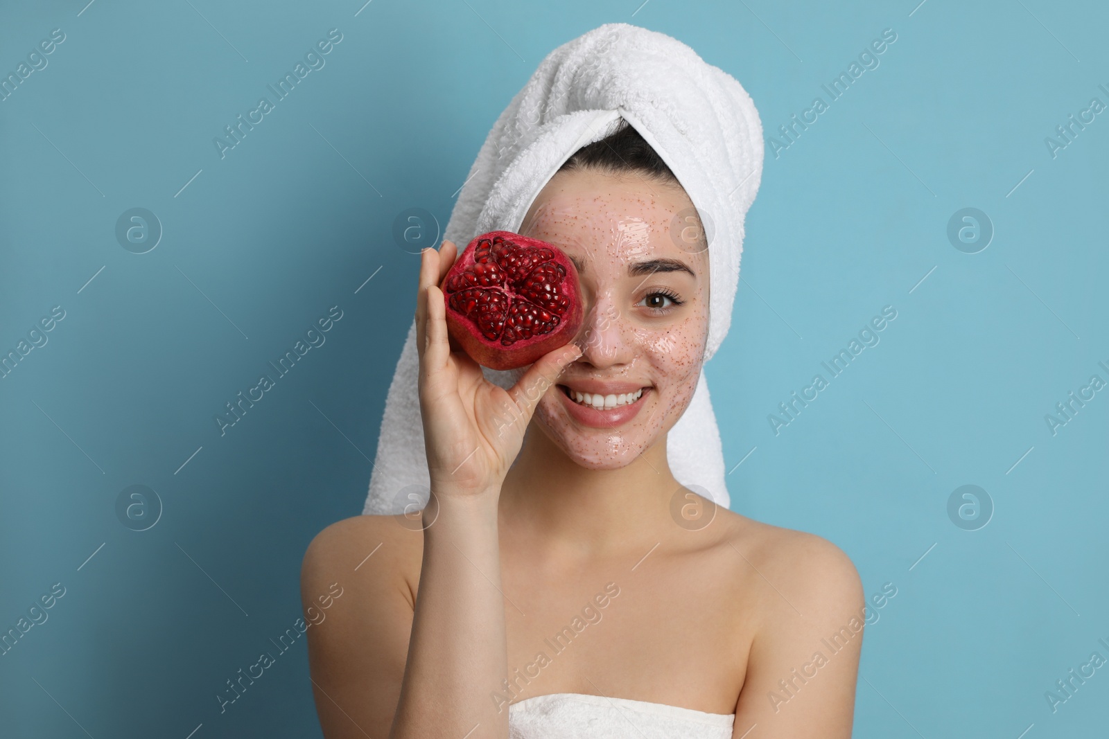 Photo of Woman with pomegranate face mask and fresh fruit on light blue background