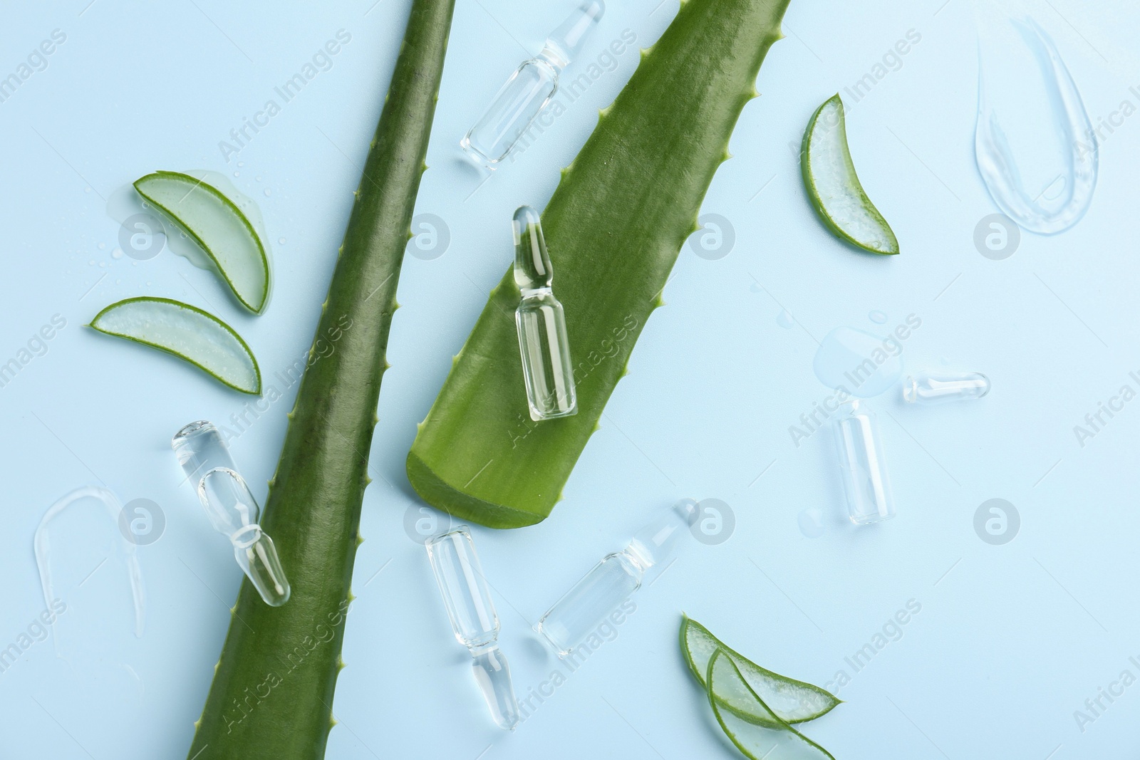 Photo of Flat lay composition with skincare ampoules and aloe leaves on light blue background