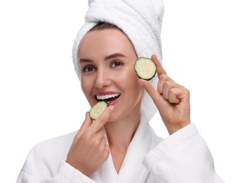 Beautiful woman in bathrobe with pieces of cucumber on white background