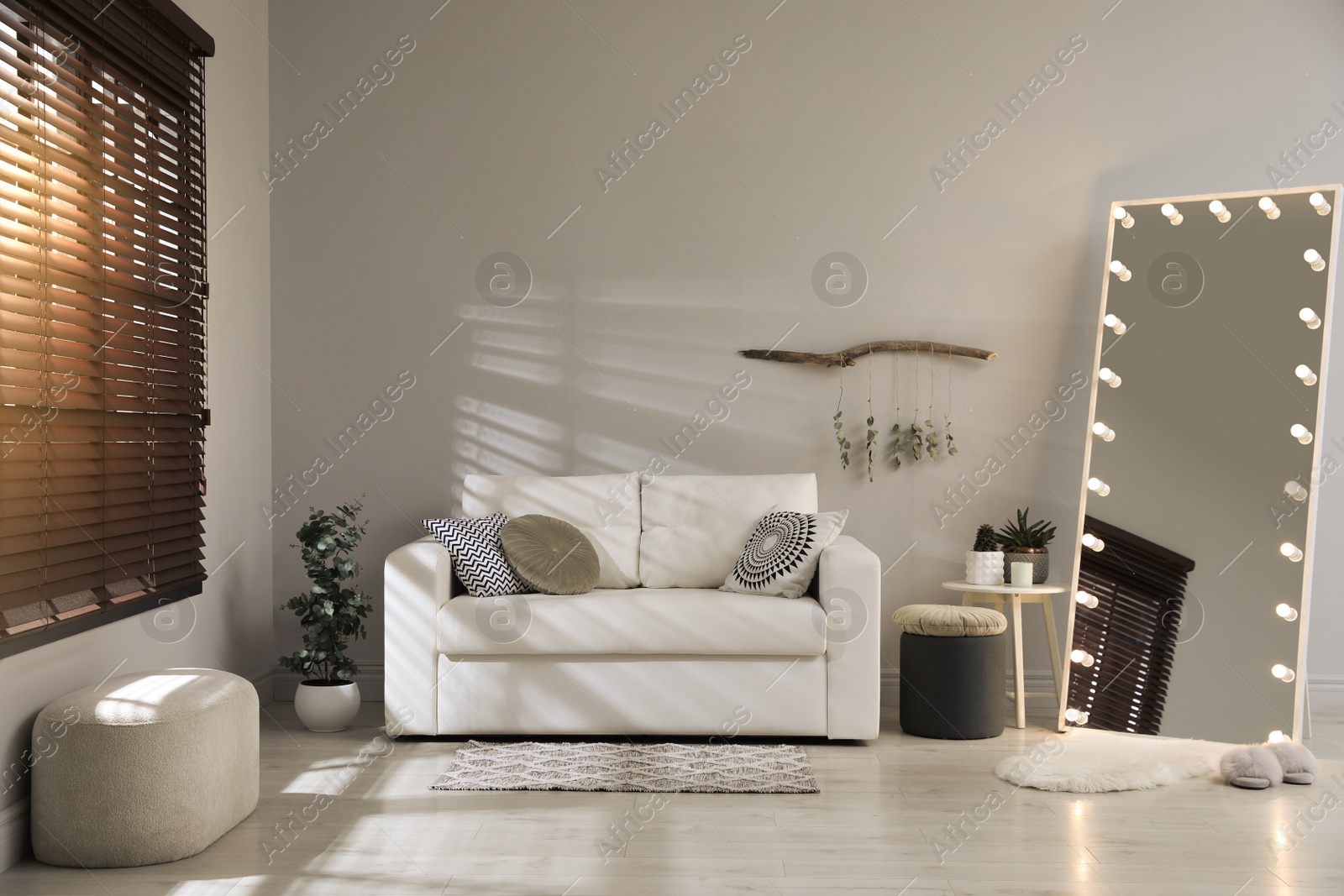 Photo of Stylish mirror with light bulbs and comfortable sofa in living room. Interior design