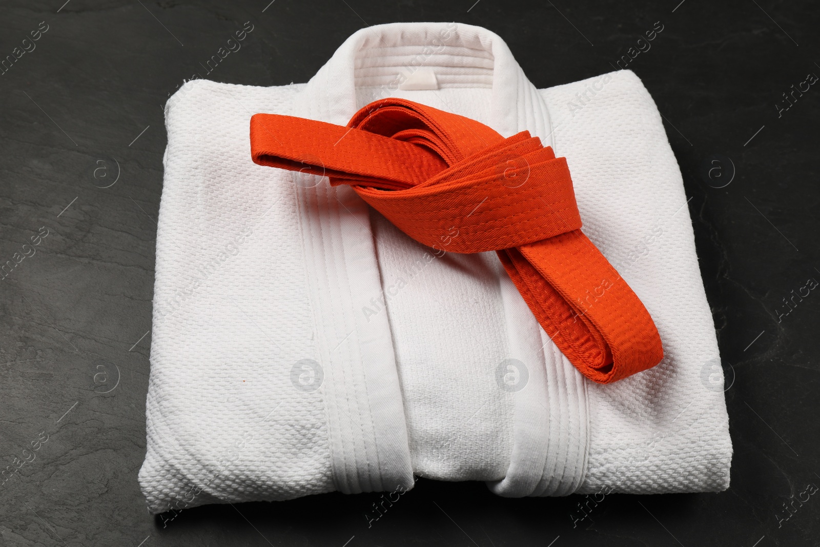 Photo of Orange karate belt and white kimono on gray background