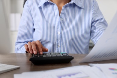 Professional accountant working at wooden desk indoors, closeup