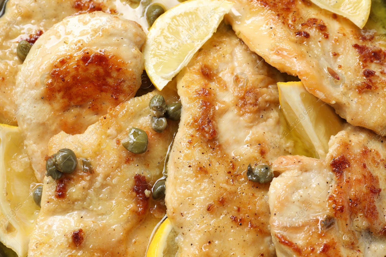 Photo of Delicious chicken piccata with lemons as background, closeup