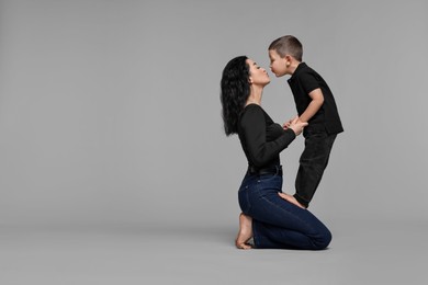 Photo of Beautiful mother with little son on grey background. Space for text