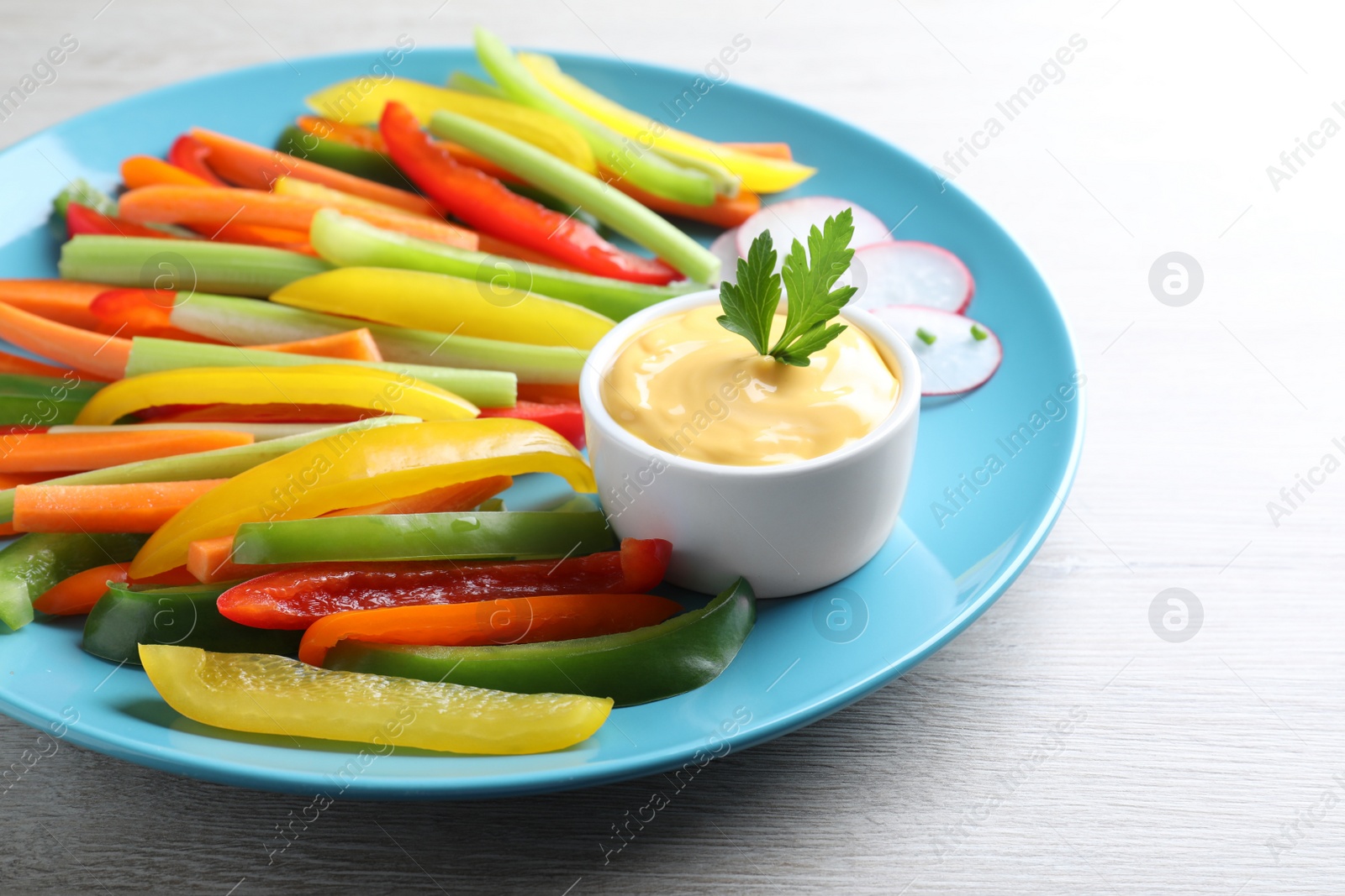 Photo of Different vegetables cut in sticks and dip sauce on grey wooden table, closeup