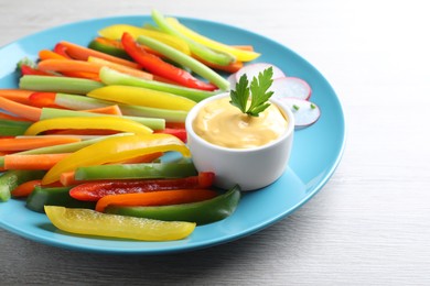 Photo of Different vegetables cut in sticks and dip sauce on grey wooden table, closeup