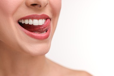 Photo of Woman with beautiful lips licking her teeth on white background, closeup. Space for text