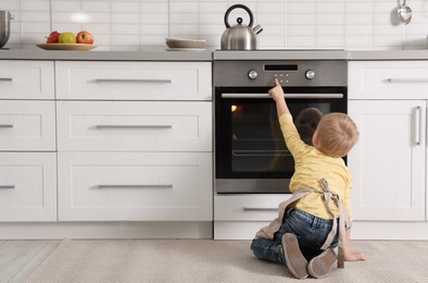 Photo of Little boy baking something in oven at home