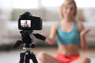 Smiling sports blogger recording fitness lesson at home, focus on camera. Space for text