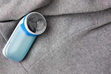 Photo of Modern fabric shaver on light grey cloth with lint, above view. Space for text