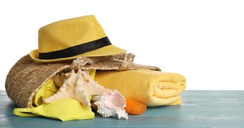 Photo of Bag with different beach objects on turquoise wooden table against white background