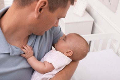 Photo of Happy father with his cute sleeping baby near crib at home
