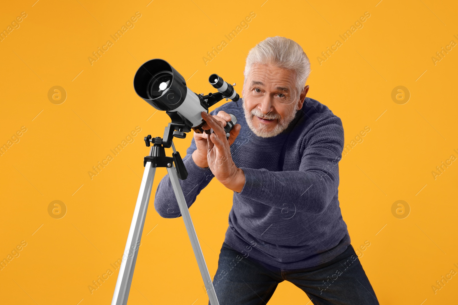 Photo of Senior astronomer with telescope on yellow background