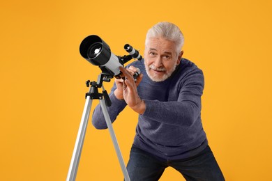 Senior astronomer with telescope on yellow background
