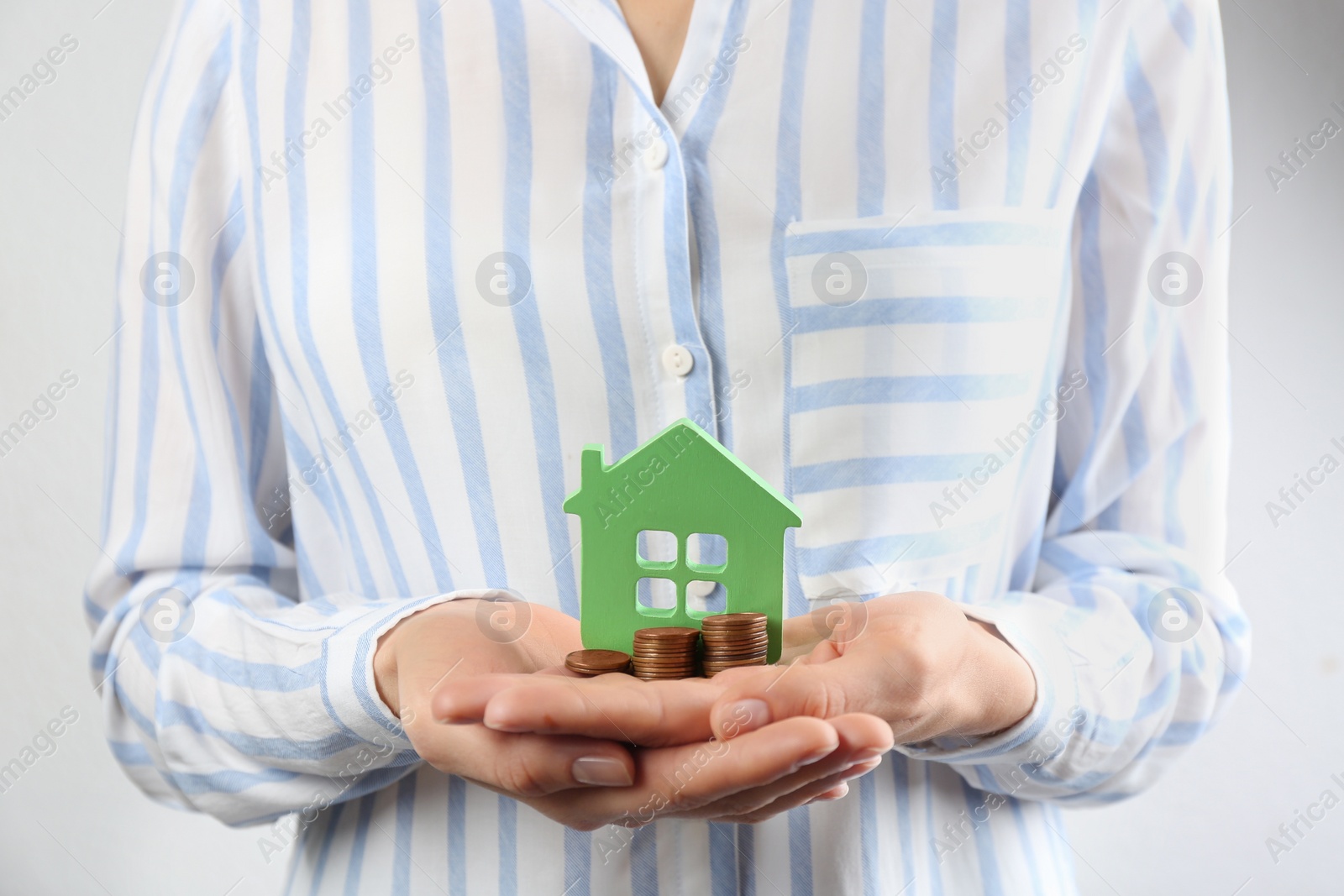 Photo of Woman holding house model and coins, closeup