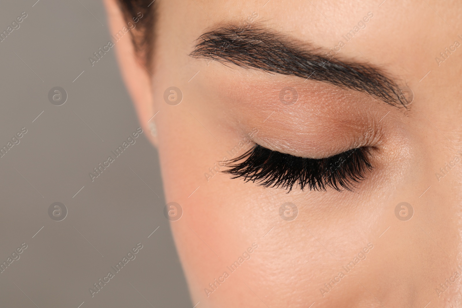 Photo of Beautiful young woman with long eyelashes on grey background, closeup. Space for text