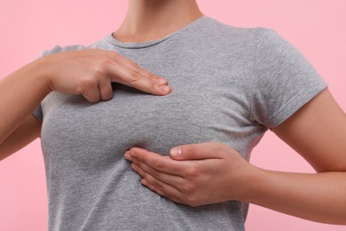 Photo of Woman doing breast self-examination on pink background, closeup