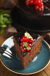 Photo of Piece of tasty homemade chocolate cake with berries and mint on wooden table, closeup. Space for text