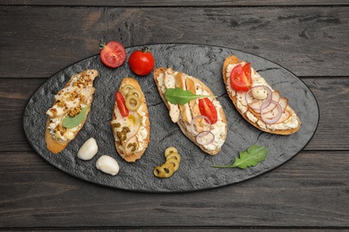 Photo of Slate plate of delicious chicken bruschettas on wooden table, top view