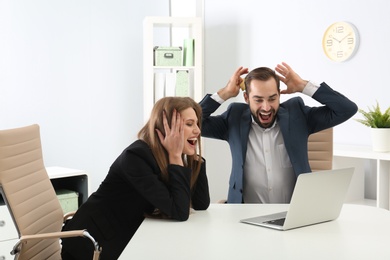 Emotional young people with credit card and laptop celebrating victory in office