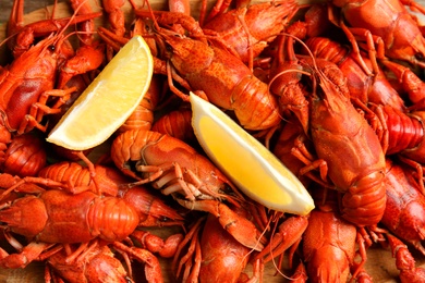 Delicious boiled crayfishes with lemon slices as background, top view