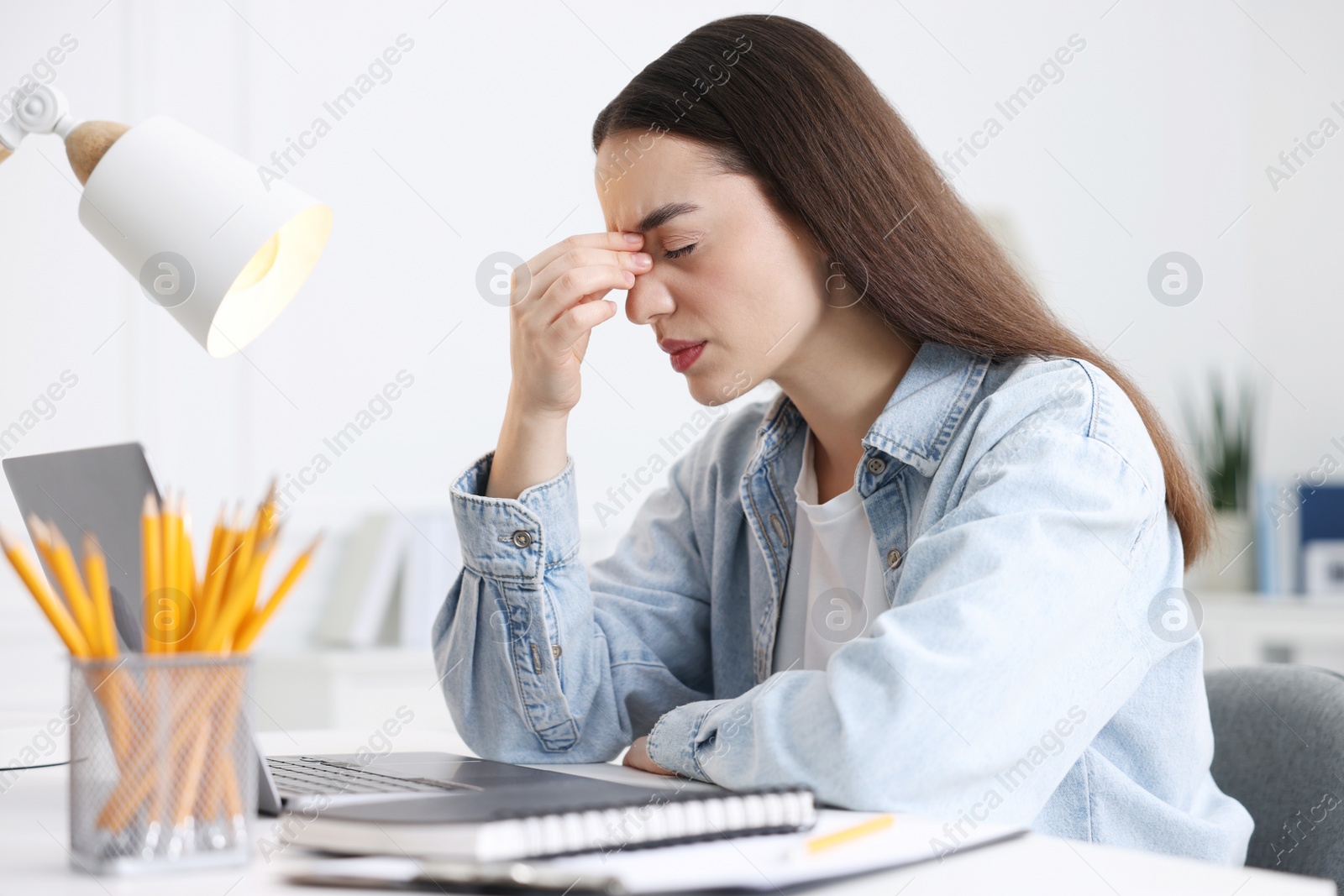 Photo of Woman suffering from headache at workplace in office