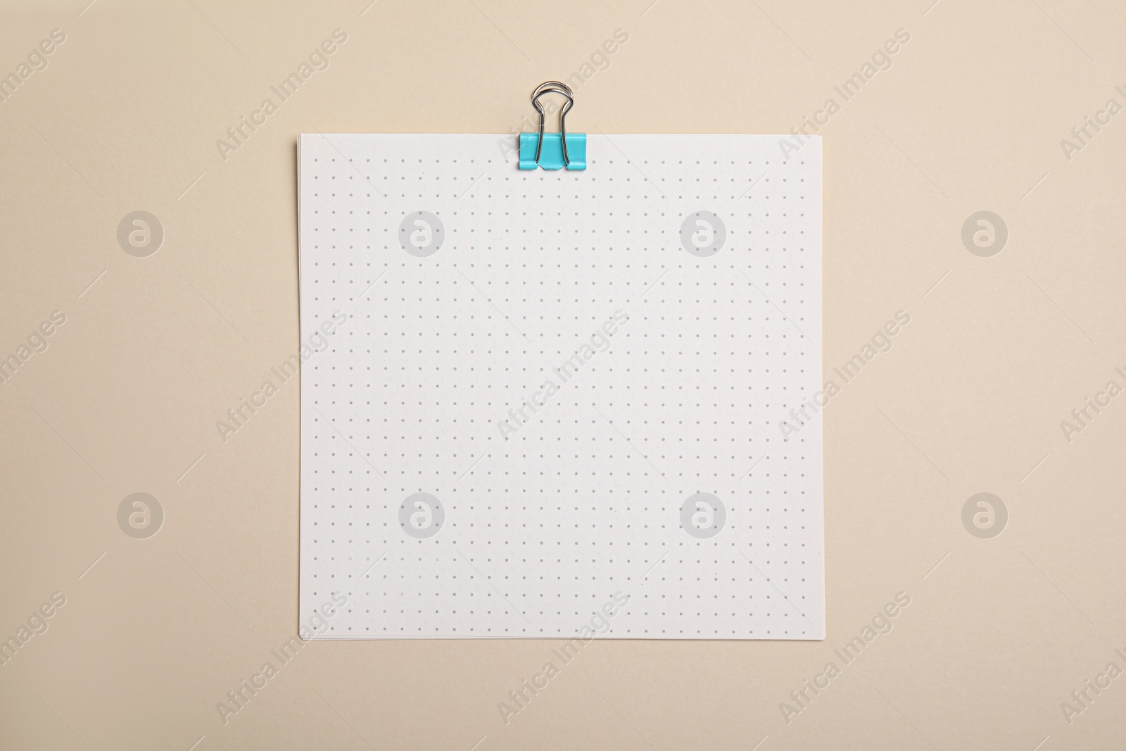 Photo of Sheet of paper with clip on beige background, top view