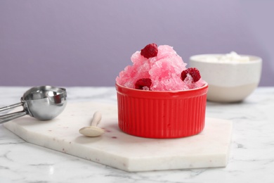 Bowl of tasty raspberry snow ice cream on table against color background. Space for text