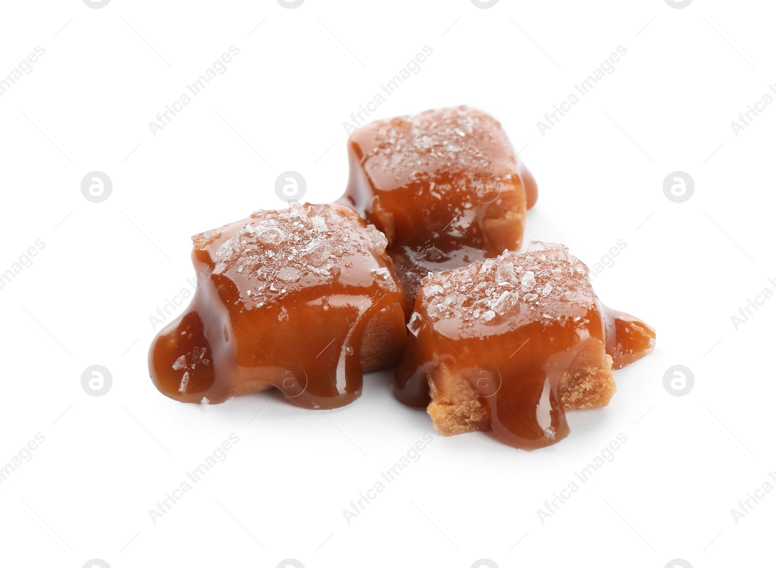 Photo of Delicious candies with caramel sauce and salt on white background