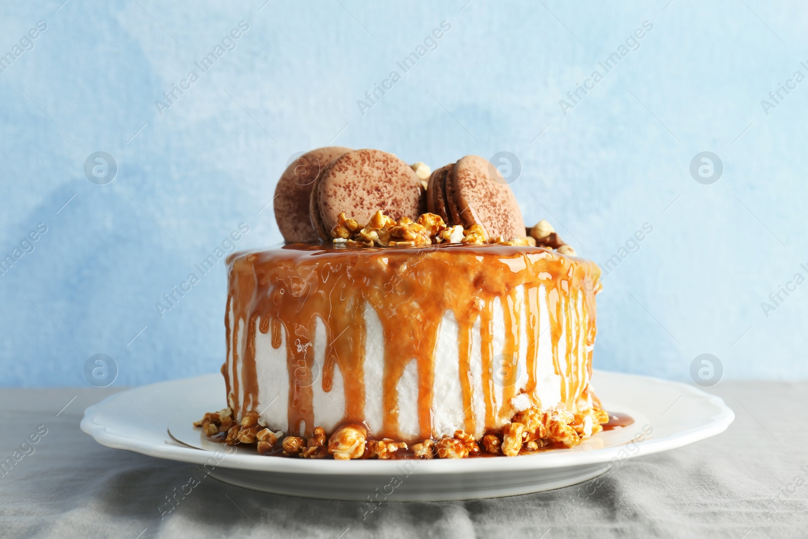 Photo of Delicious homemade cake with caramel sauce and popcorn on table