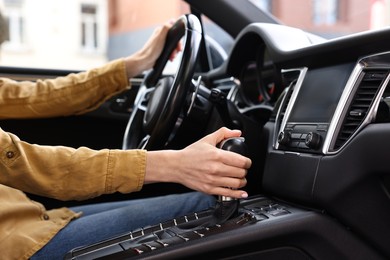 Photo of Woman using gear stick while driving her car, closeup