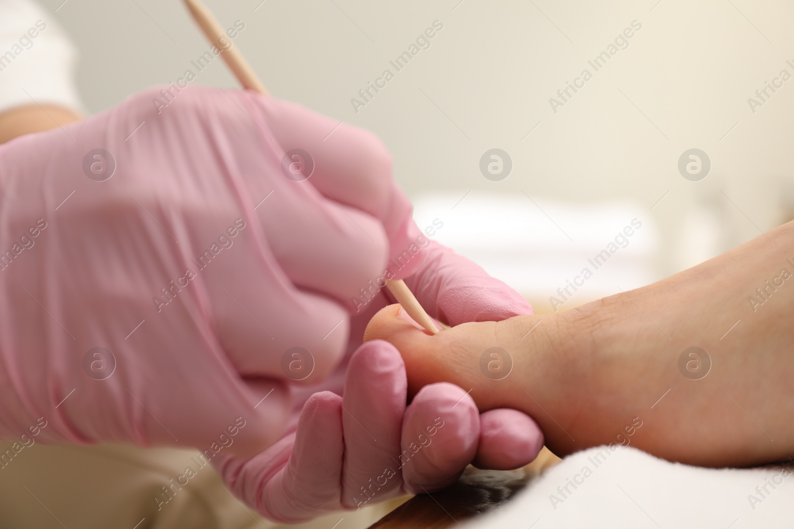 Photo of Professional pedicurist working with client`s toenails in beauty salon, closeup