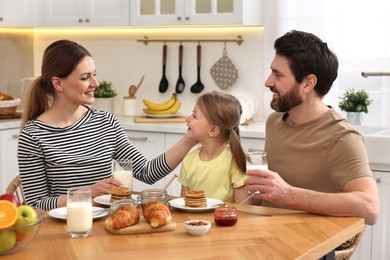 Photo of Happy family having breakfast at table in kitchen