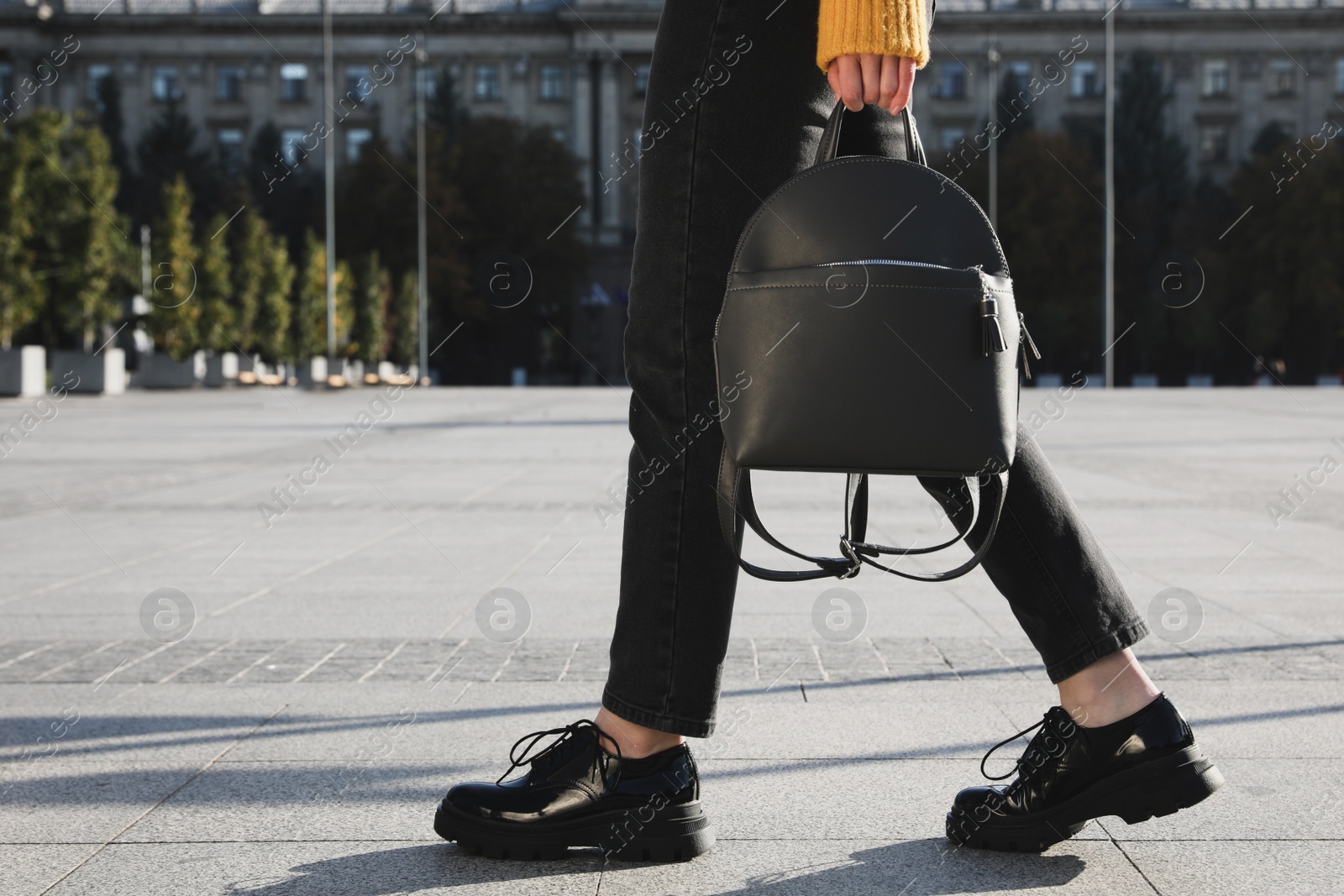 Photo of Woman with stylish black backpack on city street, closeup. Space for text