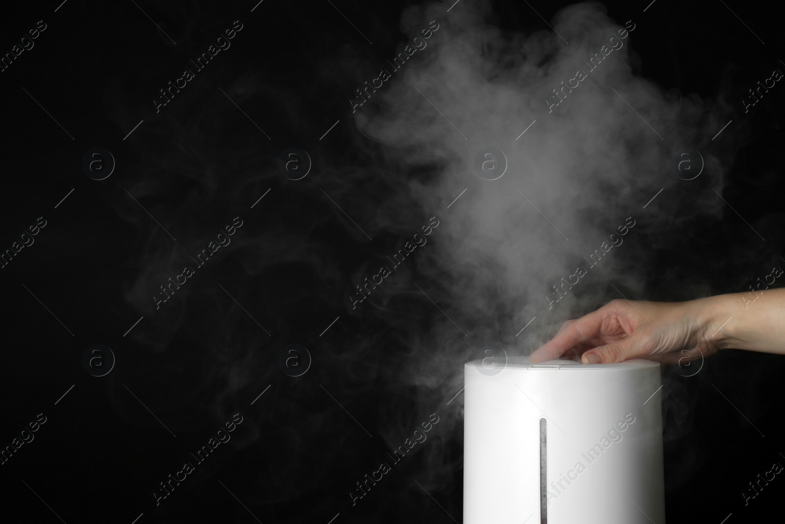 Photo of Woman using modern air humidifier on black background, closeup. Space for text