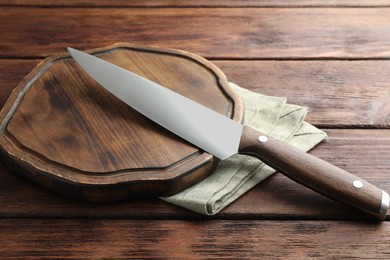 Photo of One sharp knife and board on wooden table, closeup