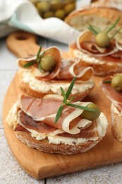Photo of Tasty sandwiches with cured ham, rosemary and olives on table, closeup