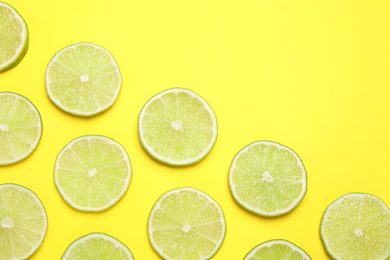 Fresh juicy lime slices on yellow background, flat lay. Space for text