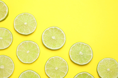 Photo of Fresh juicy lime slices on yellow background, flat lay. Space for text