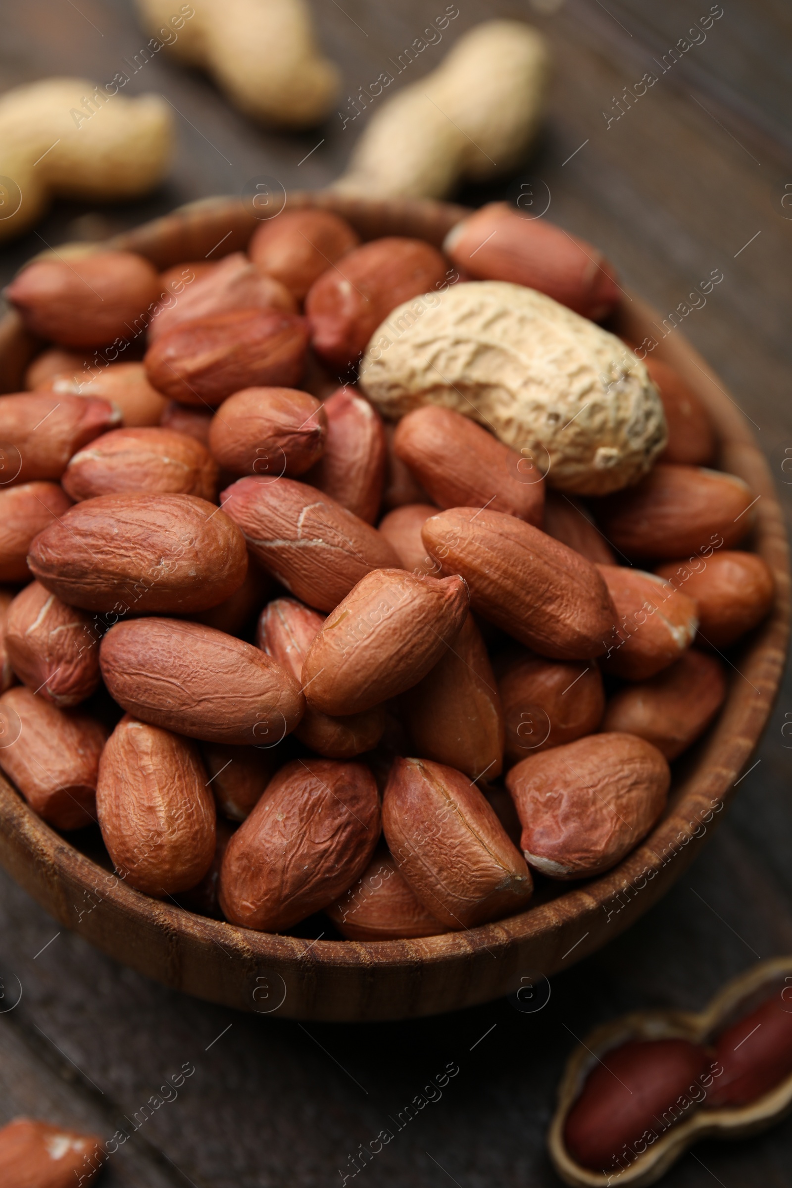 Photo of Fresh peanuts in bowl on wooden table, closeup