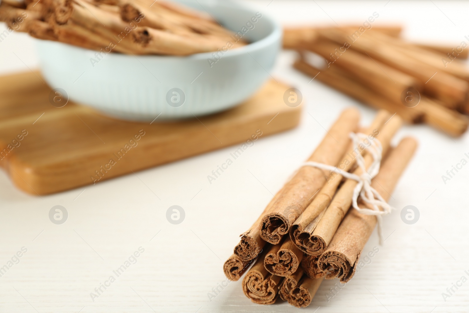 Photo of Aromatic cinnamon sticks on white wooden table, closeup