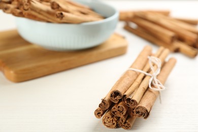 Aromatic cinnamon sticks on white wooden table, closeup