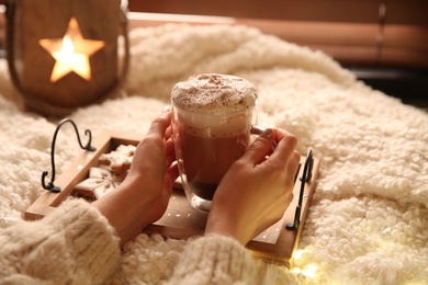 Photo of Woman with cup of hot drink and Christmas cookies at home, closeup