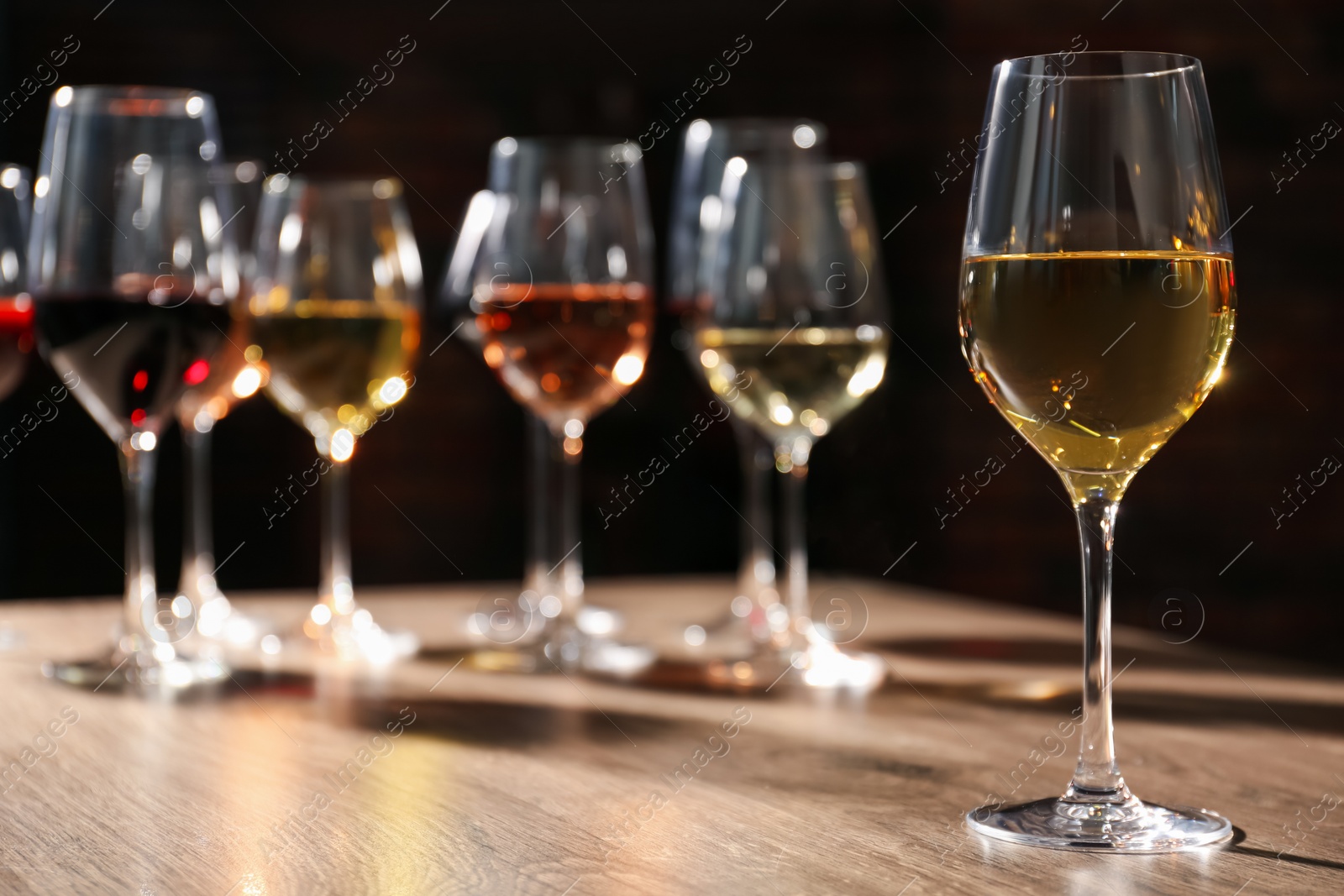 Photo of Different tasty wines in glasses on wooden table